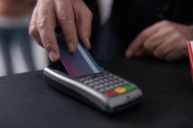 Elderly client putting credit card on pos terminal paying for pharmaceutics treatment in pharmacy, buying vitamins, supplements to help cure disease. Health care support service. Close up