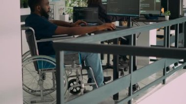 Gelişim ajansı ofisinde engelli yazım kodlu Afrika kökenli bilişim mühendisi Html betik veritabanı yazmak için terminal penceresini kullanıyor. Tekerlekli sandalye kullanıcısı güvenlik programlamasıyla çalışıyor.