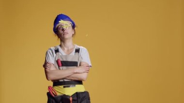 Woman construction worker being light headed after getting hit with hammer and seeing cartoonish stars. Industrial employee acting dizzy and shaky, looking confused. Looney tunes.