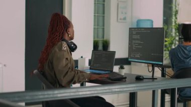 Two software coders analyzing source code on computer and laptop screen, using html script on terminal window. Team of system engineers working on cyber security innovation in it agency.