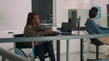 Tekerlekli sandalyedeki bulut programcısı bilgisayarda yazılım uygulaması yaratmak için sunucu verilerini kullanıyor. Ajans ofisinde yeniden kullanım arayüzü geliştirme üzerinde çalışan kodlayıcı.