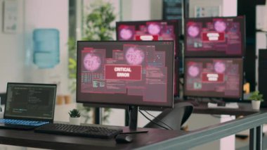 Ofis masasını, ağ uygulamasında güvenlik ihlali olduğunu gösteren birden fazla bilgisayarla boşalt. Ekranda sistem çökme uyarısı ile birlikte kritik hata iletisini gösteren monitörler.