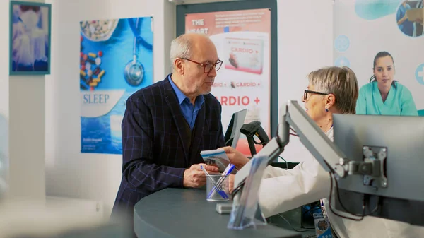 Senior Adult Talking Pharmacist Cash Register Counter Using Medical Leaflet — Stock Photo, Image