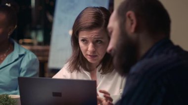 Woman talking with employee in business meeting, smiling portrait, slow motion. Colleagues discussion, brainstorming, communication in coworking space, office manager looking at camera. Handheld shot.