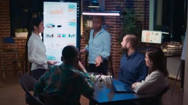 Diverse women coaching company team in business meeting, presenting sales strategy, employee listening to revenue statistcs presentation. Office workers in coworking space boardroom