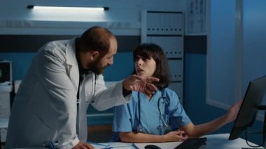 Hasta hastalıkları teşhisini tartışan hekim hekime tıbbi uzmanlığını gösteren bir hemşire birlikte sağlık tedavisi planlıyor. Personel gece geç saatlere kadar hastane ofisinde çalışıyor.