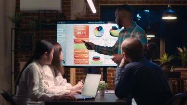 African american employee giving analytics report presentation in business meeting, showing statistics data on digital board screen. Office worker marketing research, strategy planning