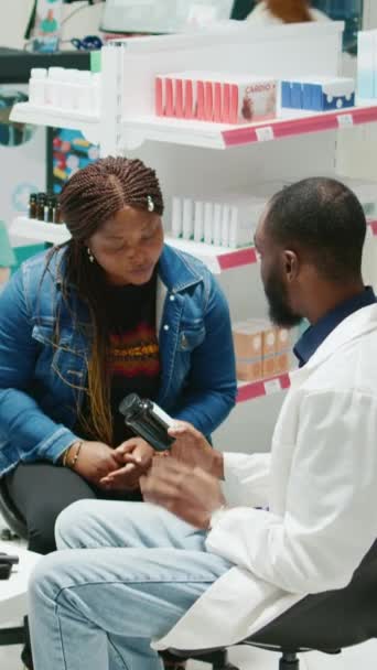 Vertical Video Young Pharmacist Giving Bottle Drugs Customers Explaining Prescription — стоковое видео