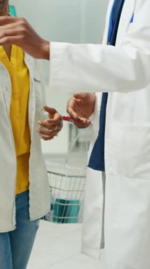 Vertical video: Pharmacy employee giving box of vitamins to client in drugstore, explaining about healthcare treatment with pharmaceutics. Specialist recommending drugs or supplements to woman.