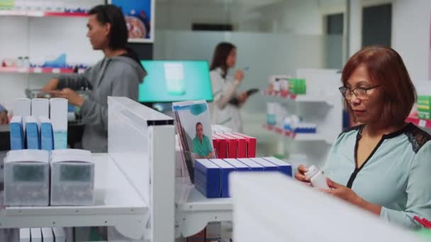 女客户在药店分析药品和药丸 寻找处方药 在装满维生素盒的药房货架里检查药品 — 图库视频影像