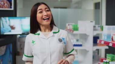 Tıbbi mağazada eczane broşürünü açıklayan kadın uzman, reçeteli tedavi ve sağlık ürünleri bulunması yönünde tavsiyede bulunuyor. Genç adam raflardaki vitaminlere ve ilaçlara bakıyor..