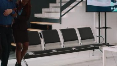 African american people helping elderly man with heart problems to sit in hospital reception lobby. Senior physician consulting old patient with stethoscope, trying to cure cardiovascular illness.