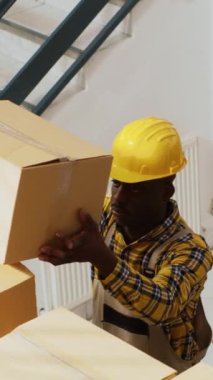 Dikey video: Depoda ürün lojistiği üzerinde çalışan bir grup iş arkadaşı, depodaki ürün paketlerini kontrol ediyorlar. Depo çalışanlarından oluşan neşeli bir ekip stok envanteri çıkartıyor.