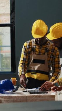 Dikey video: Depo malzemeleri ve stok ürünleri için dizüstü bilgisayar kullanan bir ekip. Raflarda kutular ve paketlerle ürün dağılımı üzerinde çalışmak, kalite kontrolü.