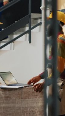 Dikey video: Genç depo çalışanları gülerek ve şakalar yaparken, perakende satış mağazası ürünleri üzerinde çalışılıyor. Eğlence deposunda eğlenen, iş yerinde neşeli insanlardan oluşan bir üretim ekibi..