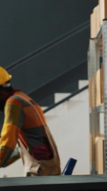 Dikey video: Perakende işçileri depodaki erzak paketlerini kontrol ediyor, bilgisayar üzerinden kalite kontrol üzerinde çalışıyor. Kutularda ürün veya mal taşıyan genç çalışanlar, ulaşım