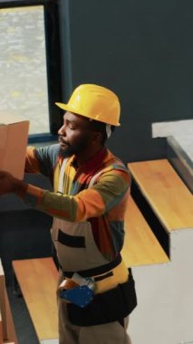 Dikey video: Depo çalışanlarından oluşan bir ekip malzemeleri raflardan indiriyor, karton paketlerdeki perakende mağaza stoklarını kontrol ediyor. Çalışanlar depoda merdiven kullanıyor, malları nakliye için hazırlıyorlar..