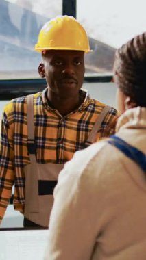 Dikey video: Mutlu çalışanlar depoda eğleniyor, imalat malzemeleri ve stok dağıtımı üzerinde çalışıyor. Ürünlerle gülen ve plan yapan insanlardan oluşan bir ekip. El kamerasıyla..