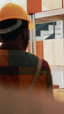 Dikey video: Afro-amerikan erkekler stok dağılımını planlıyorlar raflarda kargolarla, depodaki ürün barkodlarını tarıyorlar. Envanteri kontrol etmek için tarayıcı ve tabletle çalışan gençler