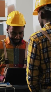 Dikey video: Depo alanında dizüstü bilgisayarla nakil yapmayı planlayan çalışanlardan oluşan bir ekip, sevkiyattan önce perakende ürünlerle paketleri kontrol ediyor. Depoda kalite kontrol üzerinde çalışan insanlar.