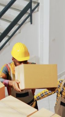 Dikey video: Depo işçileri malları paketler halinde düzenliyor, raflara ve raflara kutular koyuyorlar. Bir grup insan depoda kutu kutu ürün alıyor, konteynırlarla çalışıyorlar. El kamerasıyla..