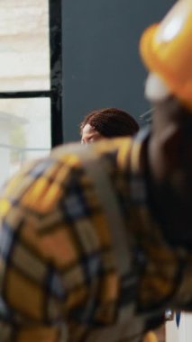 Vertical video: Workers team preparing goods shipment on shelves, working with merchandise in cardboard boxes. People doing inventory for retail store production, stacking packages on racks. Handheld