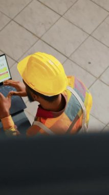 Dikey video: Kağıt üzerinde lojistik listesini inceleyen insanlar dizüstü bilgisayar ve pano ile envanter envanteri üzerinde çalışıp raflardaki malları kontrol ediyorlar. Siparişlerle birlikte üretim için planlama nakliyesi