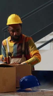 Dikey video: Depo ekipmanları kullanan, paketlerle ambalaj bölümünde çalışan bir grup eğitimli işçi. Ürünleri paketlemek ve nakletmek için ticaret kutuları kullanan insanlar, endüstriyel stoklar.