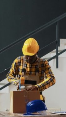 Dikey video: Afro-amerikan insanları ürünlerle dolu kutuları paketliyor, sevkiyat için stok hazırlıyorlar. Genç depo çalışanları, malları karton paketlere, malları raflara koyuyorlar..