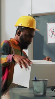 Dikey video: Afrika kökenli Amerikalı çalışanlar depo envanterindeki kargo paketlerini kullanarak kutularda kargo taşıyorlar. Erkek ve kadın stokları dağıtım ve sevkiyat için hazırlıyor, kalite kontrol.