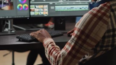 Genç grafik tasarımcısı, odaklı ışıklandırma ve renk derecelendirme kullanarak yazılım üzerinde video içeriğini düzenliyor. Erkek film yapımcısı pc multi monitörlerinde montaj üzerinde çalışıyor, görüntü yönetmeni.
