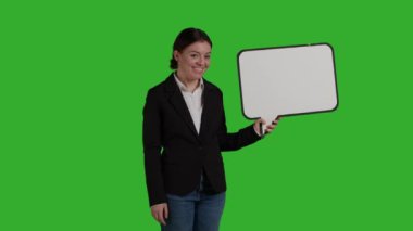 İşletme müdürünün kamerada konuşma baloncuğu tutuşu, izole edilmiş karton simgeyi yeşil ekran arkaplanının üzerinde gösteriyor. Takım elbiseli kadın stüdyoda boş telif alanı olan karton tahta kullanıyor..