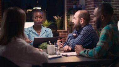 Stratejik planlama iş toplantısı, Afro-Amerikan çalışan konuşması, çeşitli iş arkadaşlarının beyin fırtınası yapması, strateji tartışması. Ofis çalışanları birlikte çalışan uzay masasında konuşuyor. Üçayak atışı.