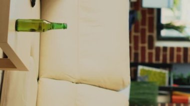 Vertical video: Smiling girl preparing to eat slice of pizza at tv, sitting on couch and watching comedy movie. Cheerful modern woman eating dinner from fast food meal delivery, drinking alcohol at