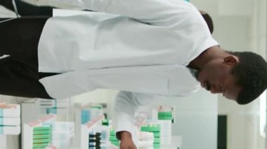 Vertical video: Male client checking boxes of vitamins on shelves, looking to buy pills and medical healthcare products. Person analyzing medicaments and drugs from pharmacy shop, drugstore service.