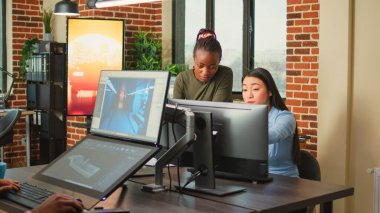 Çeşitli meslektaşlar, profesyonel bilgisayar yazılımı kullanarak yaratıcı ajans stüdyosunda 3 boyutlu içerik yaratmak için fikir üretmeye çalışıyorlar. Dijital proje geliştirme üzerinde çalışan genç bayan çalışanlar.