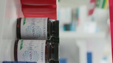 Vertical video: African american client taking pills from shelves in drugstore, looking to buy medicaments and vitamins. Woman buying prescription medicine and drugs to cure disease. Close up.