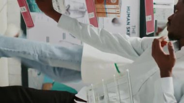 Vertical video: Young adult looking at packs of vitamins in drugstore, checking pharmaceutical products from racks. Male customer taking medicaments and supplements from shelves, pharmaceutics store.