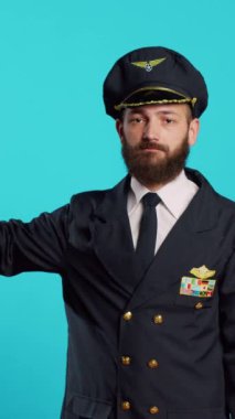 Vertical video: Professional aviator showing thumbs down sign, expressing dislike and bad negative gesture. Airline pilot in uniform doing disapproval and failure symbol, commercial flights occupation