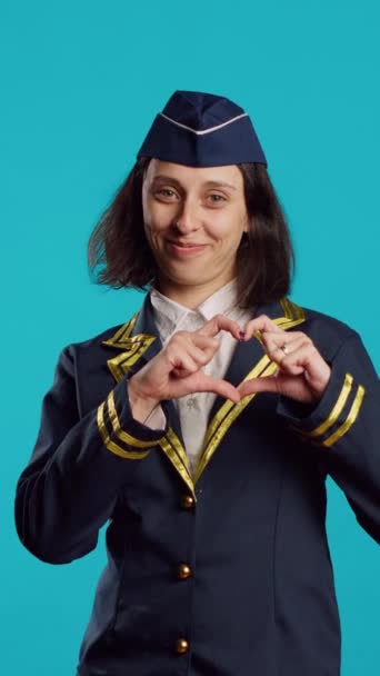 垂直视频 积极的空姐用手展示心形符号 在工作日表达浪漫的感觉和爱情 作为空姐工作的年轻女人 在浪漫的姿态下感到甜蜜和可爱 — 图库视频影像