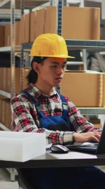 Vertical video: Asian man planning shipment of orders in storage room, working with female employee to send packages for supply chain. Team of people checking merchandise and products, small business.