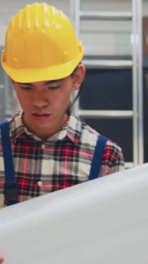 Vertical video: Female wheelchair user checking logistics on laptop in warehouse space, working with employee to send products packages. Person with physical disability doing quality control, small