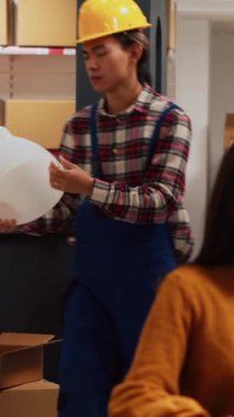 Vertical video: Group of asian people looking at merchandise stock in storage room, checking products before shipment. Depot employees working on quality control for distribution, small business