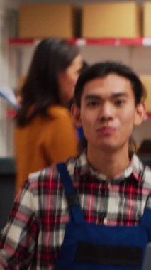Vertical video: Young man promoting products on online ad video, recording promotion for internet channel. Male adult creating advertisement with mobile phone, filming marketing vlog. Handheld shot.
