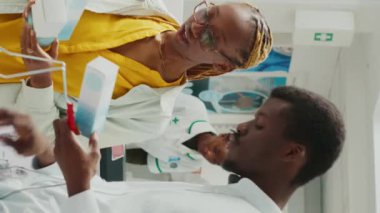 Vertical video: Man and woman looking for healthcare products in pharmacy, checking packages of medicaments and supplements. People buying prescription treatment or vitamins bottles. Tripod shot.