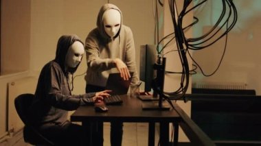 Mysterious spies working on phishing and cryptojacking, trying to break into government server and steal valuable data. Team of hackers with anonymous masks hacking online system.