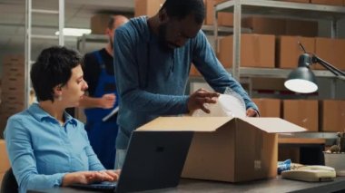 Entrepreneurs team preparing shipment order with products from warehouse racks, working on delivery logistics with laptop. Diverse people planning business development, supply chain.