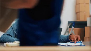 Kadın ve erkek depoda depo envanteri yapıyor. Mal ambalajlarını ve tedarik zincirlerini kontrol ediyorlar. Girişimcilerden oluşan bir ekip raflardaki ürünlere ve nakliye ürünlerine bakıyor. Üçayak atışı.