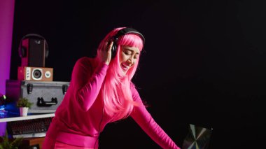 Happy musician enjoying playing electronic song at professional mixer console, performing techno music in front of crowd. Asian artist doing performance at nightclub with audio equipment