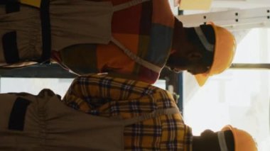Dikey video: Lojistik ve envanter için barkodlu kutuları tarayan genç işçiler konteynır malzemeleri ile çalışıyorlar. Tarayıcı ve dijital tablet kullanan, mal paketlerini kontrol eden adamlar